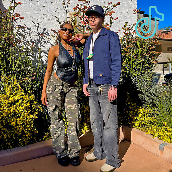 2 people standing in front of plants wearing spring outfits