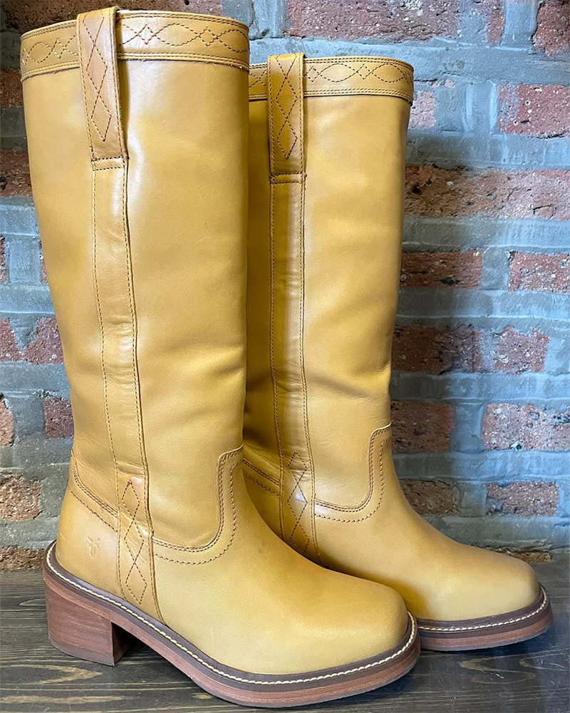 Banana Frye Campus Boots sit on a shelf in front of brick wall