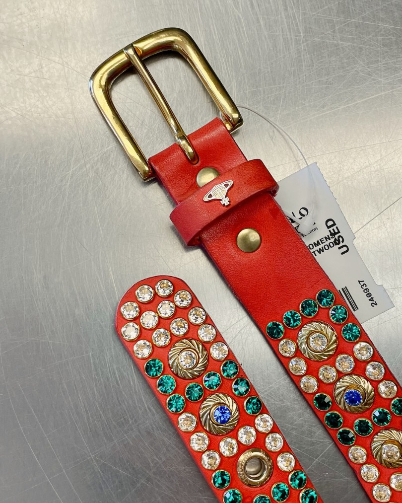 Coral red belt from Vivienne Westwood with colorful white, green, and blue rhinestones on the buy counter at Buffalo Exchange
