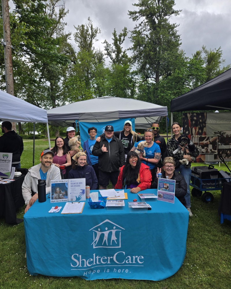 Sheltercare volunteers posing for group photo behind booth
